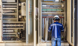 Worker Installing Hardware on Large Automation Panel